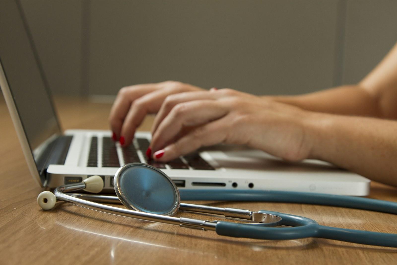 Clinician working at a laptop beside a stethoscope
