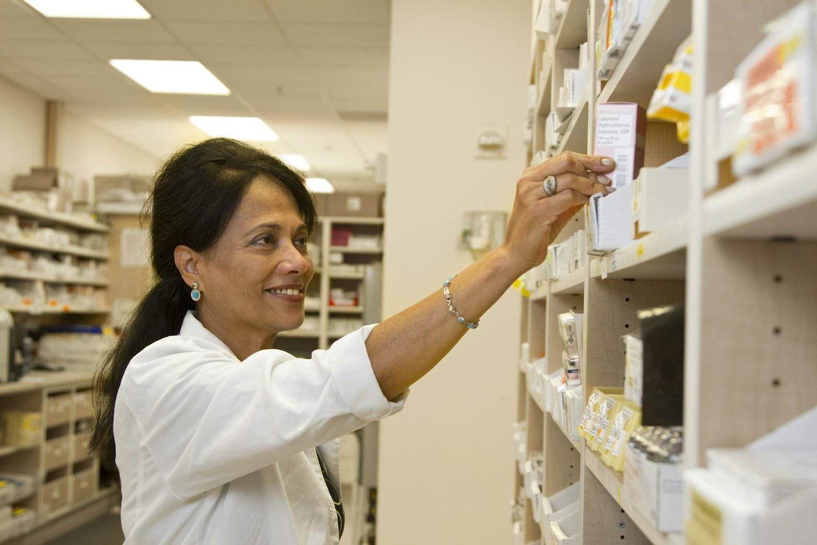 Pharmacist reaching for medicine on a shelf